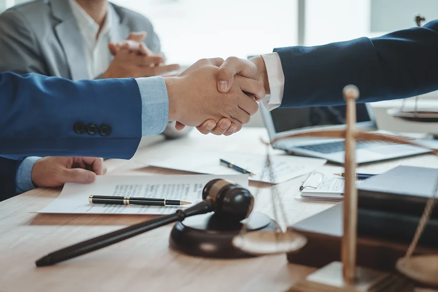 Poignée de main entre professionnels de l'administration fiscale, avec un marteau judiciaire et une balance au premier plan